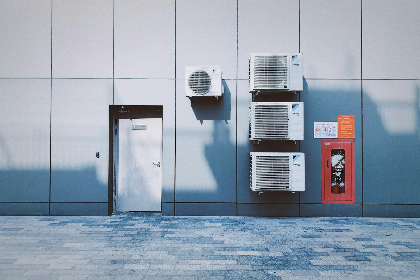 Row of wall-mounted AC units outside a commercial building